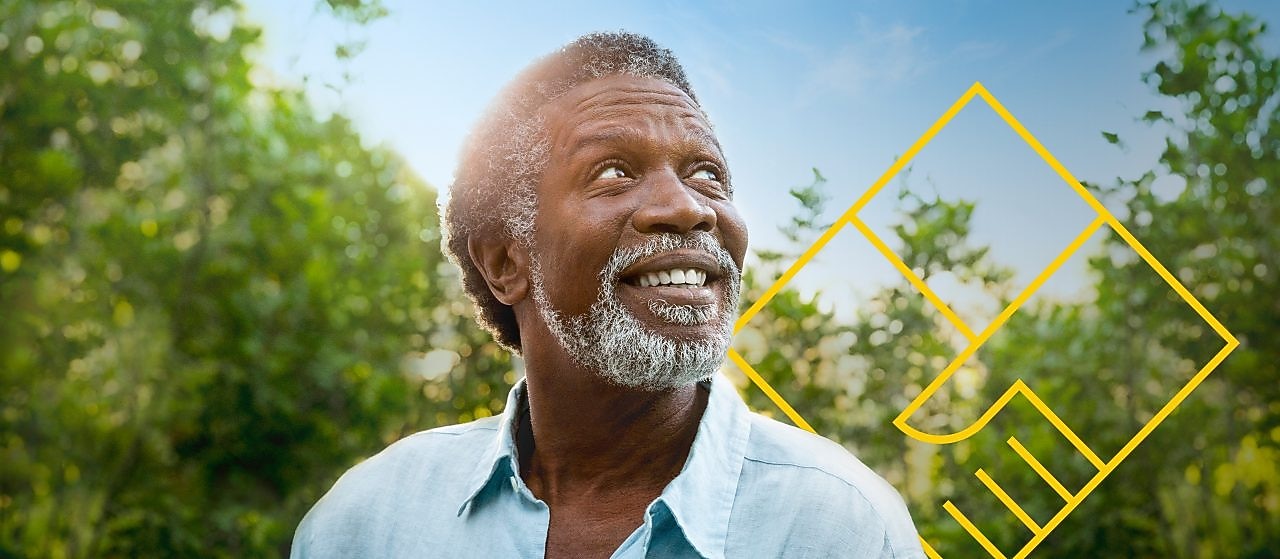 株主価値の創出を説明したグラフの概要を示しながら、樹木の前で笑顔を見せる男性