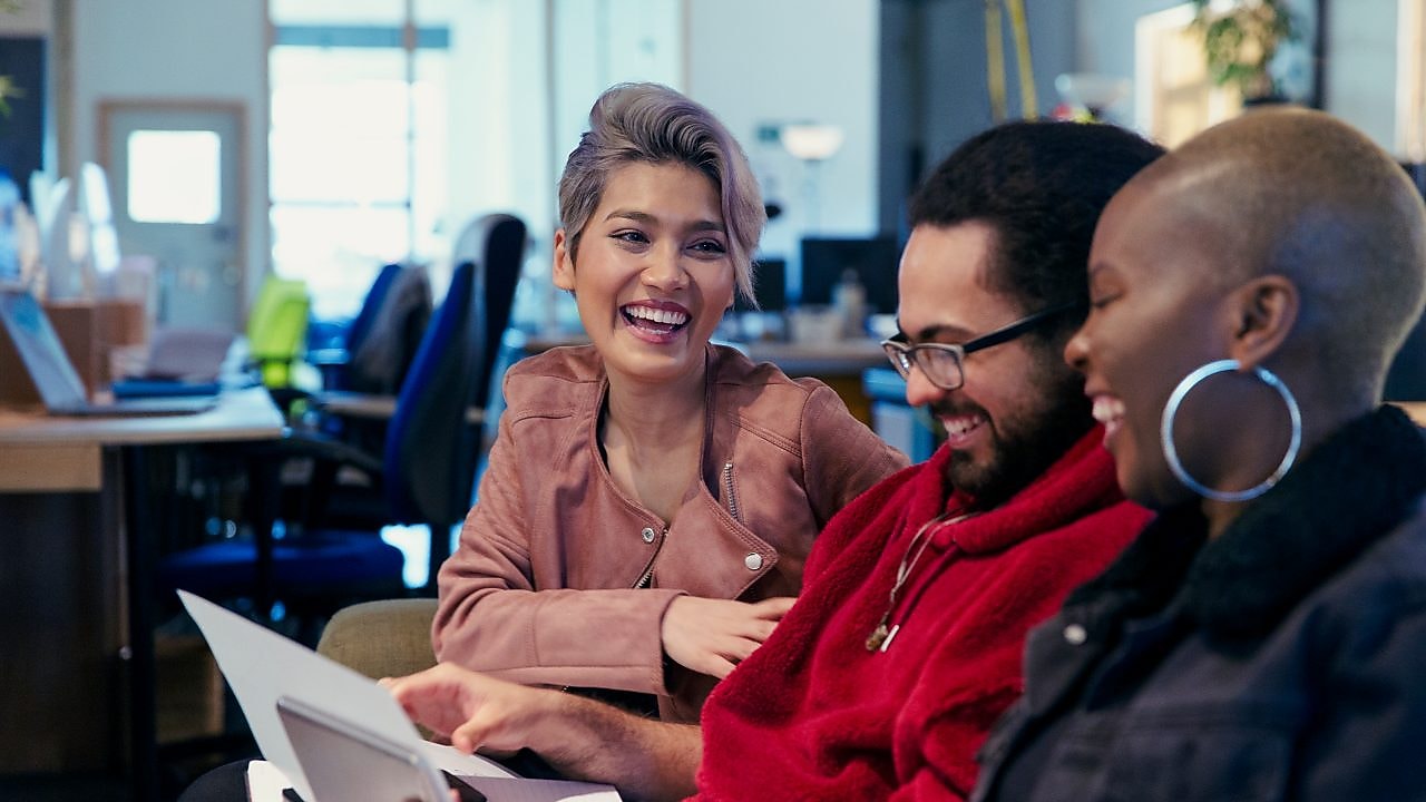 オフィスで一緒に座って、書類を眺めて笑い合う三人